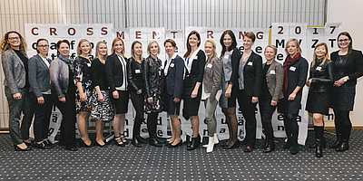 Siebzehn Damen stehen unter einem Transparent mit dem Titel "Cross Mentoring 2017".