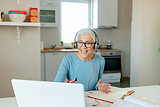 Ältere Frau mit Headset arbeitet im Homeoffice ©iStock/PixelsEffect